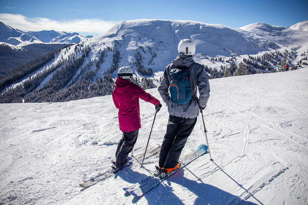 A female skier and male skier look across the ski slopes of Copper Bowl at Tucker Mountain, expert terrain located at Copper Mountain.