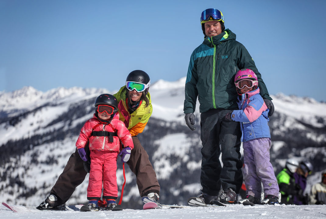 A family of four – a mother, a father, and two small children – smile for the camera as they stand in their ski gear at Copper Mountain.