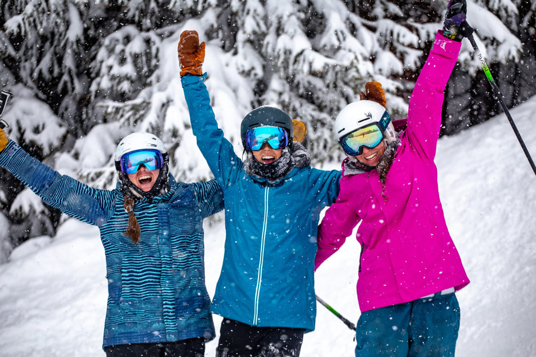 Three women smile for the camera while it snows at Copper Mountain.